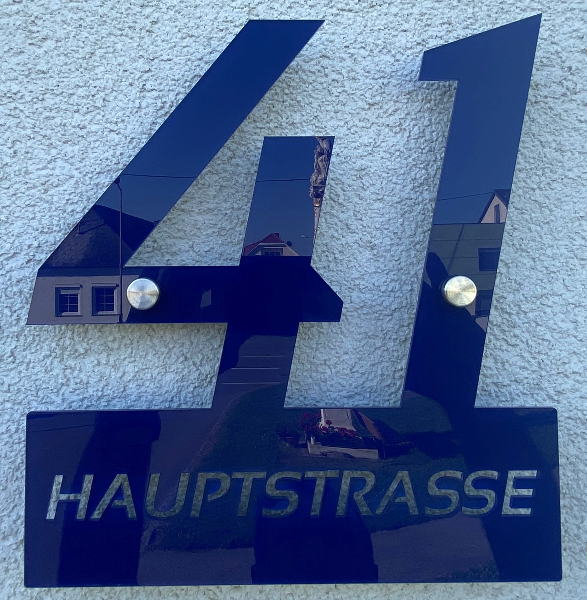 Hausnummer 41, Hauptstraße, modernes Design auf weißer Wand, spiegelt umliegende Gebäude wider.