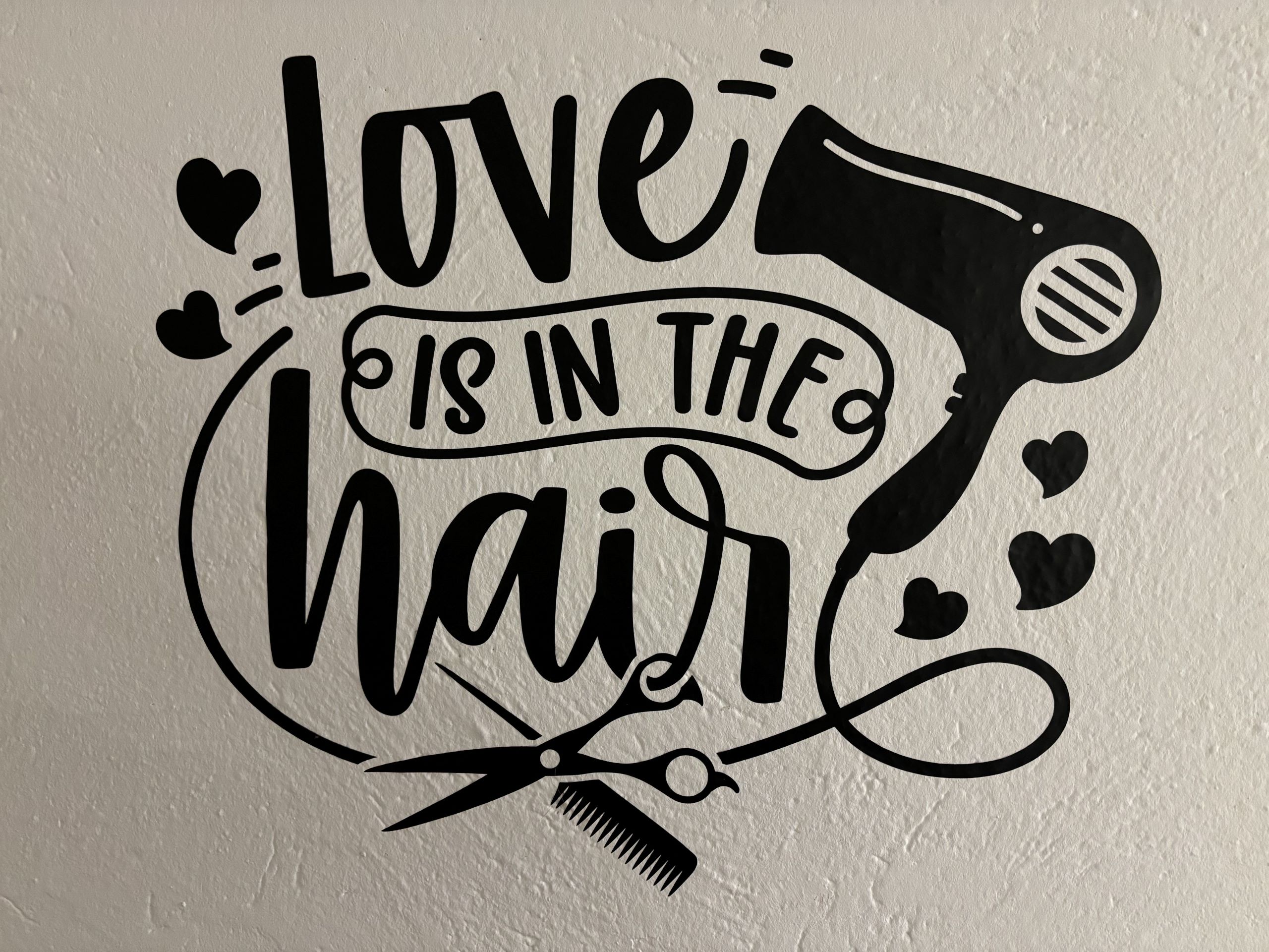 Friseur-Wandtattoo mit Spruch Love is in the hair, Föhn, Scheren und Herzen – perfekt für den Salon.